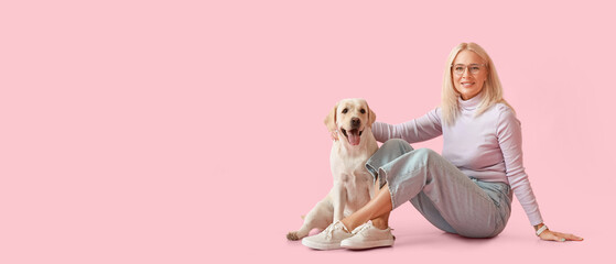 Mature woman with cute Labrador dog on pink background with space for text