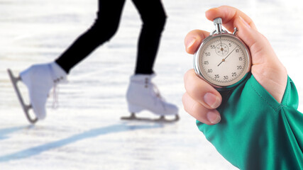 measuring speed on skates with a stopwatch. hand with a stopwatch on the background of the legs of...