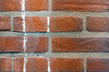 Texture of a red brick wall with cement masonry and white paint streaks