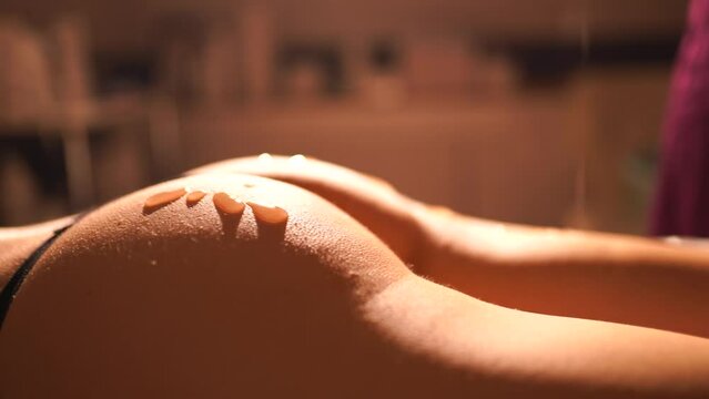 Preparation for massage: master masseur apply cream to hips and buttocks of a female client. Relaxing treatment. Slimming and body shaping.