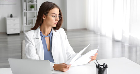 Beautiful young businesswoman working with papers in modern office