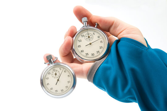Two mechanical stopwatches hang on the fingers of a male hand. Time part precision. Measurement of the speed interval