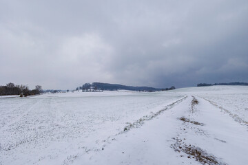 snowy field path with cloudy sky in Schmuttertal biotope near the village of Gablingen near Augsburg in Bavaria, Germany