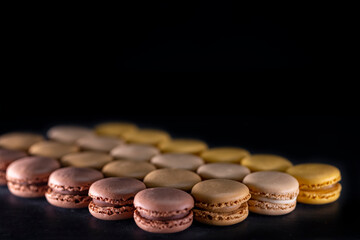 chocolate, coffee, vanilla, lemon and strawberry macaroons on black background