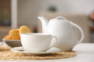 Cup of hot tea and pot on table in cafe