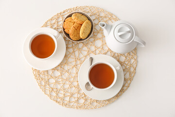 Cups of hot tea and pot on white background