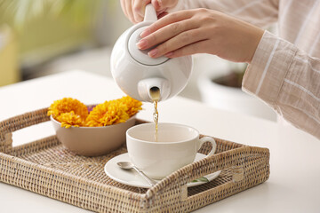Woman pouring hot tea into cup at table in cafe