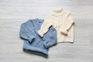 Children's knitted sweaters on grey wooden background