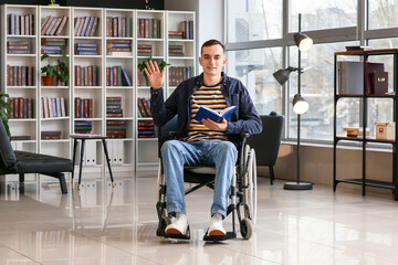 Young man in wheelchair reading book at home