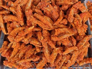 Close - up shot deliciously colorful cooked fried chicken wings. placed on an aluminum grille to prepare for sale. street food concept.