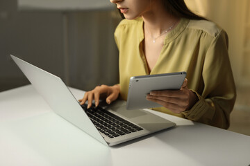 Beautiful businesswoman working with laptop and tablet computer in office at night