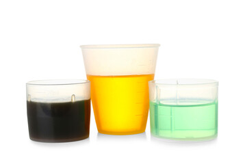 Measuring cups of cough syrup on white background