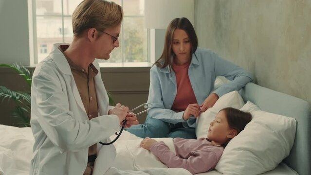 An Asian mom called a Doctor who checks the health status of a sick Asian child.