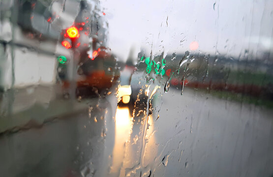 Blurred view of city traffic through wet car window with rain drops