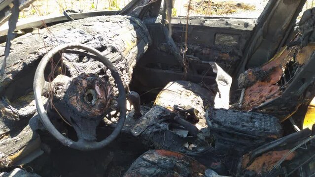 Wreck of a car burned in a fire. Melted seats, dashboard and steering wheel of abandoned vehicle, destroyed in a traffic accident, riots or war.