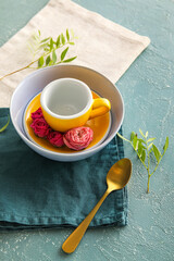 Table setting with cup, tea spoon and floral decor on color background