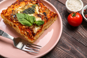 Plate of tasty Italian pie with mozzarella and pesto sauce on wooden background, closeup