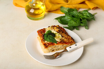 Plate of tasty Italian pie with mozzarella and pesto sauce on light background