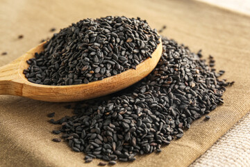 Spoon with black sesame seeds on table, closeup