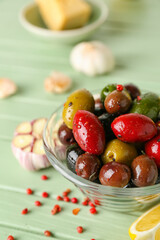 Bowl of delicious olives with spices on color wooden background, closeup