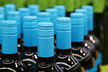 Wine bottles with blue lids in a row. Liquor store, red wine production concept