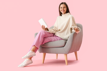 Fototapeta na wymiar Beautiful woman with book sitting in armchair on pink background