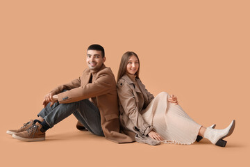 Fashionable young couple in autumn clothes on beige background