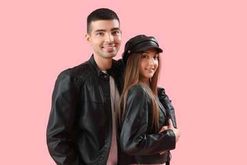 Fashionable young couple in autumn clothes on pink background