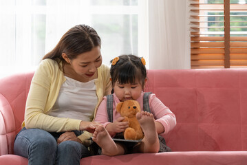 Asian Mother Watching Cartoon From Digital Tablet with Young Daugter in Living Room
