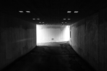 Concrete tunnel dimly lit in black and white. No visible people.