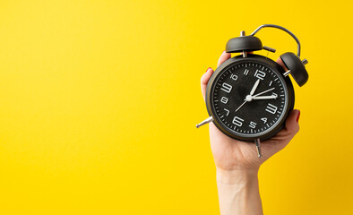 Black friday concept. First person top view photo of female hand holding black alarm clock on...