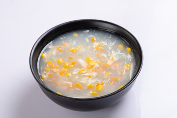 Chicken corn and chicken soup in a bowl macro on white background in a black bowl .