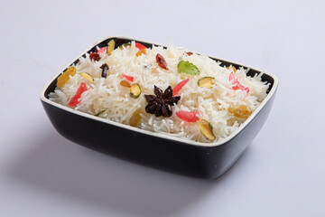 Star anise placed on cooked rice with use of selective focus on a particular part of the star anise with rest of the star anise, the cooked rice and background blurred.