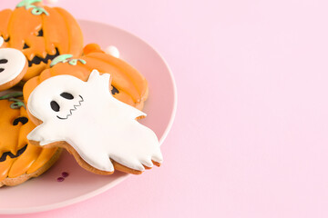 Plate with Halloween cookies on pink background, closeup
