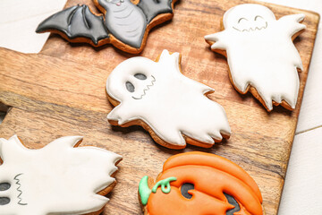 Board with Halloween cookies on white wooden background, closeup