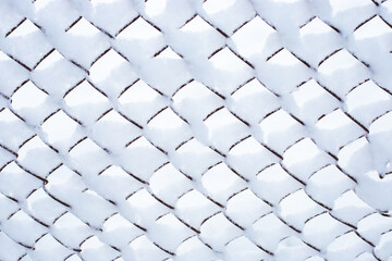 Iron mesh netting covered with white snow. Winter background