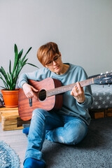  Woman with short hair enjoys playing guitar at home. Music lessons for adults