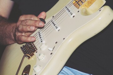 Tocando una guitarra eléctrica en una actuación. Mano con una uña sobre las cuerdas de la...