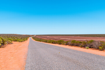 Scenic winding road in Western Australia. Remote asphalt track in Australian bushland with red sand