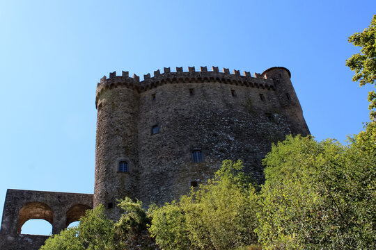 I merli a coda di rondine del Castello di Fosdinovo stagliati nel cielo con alberi