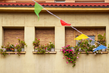Fototapeta na wymiar Window of an ancient residential building with flowers, festive flags