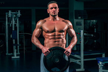 Fototapeta na wymiar Powerlifter with heavy weight disk in sport gym. Bodybuilder training his biceps.