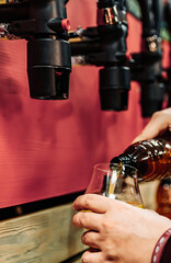 bartender hand at beer tap pouring a draught beer in glass in tap room