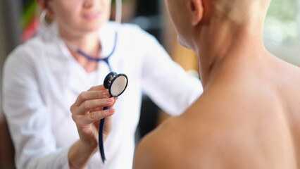 Doctor listens to heart and lungs of young athlete man closeup with stethoscope