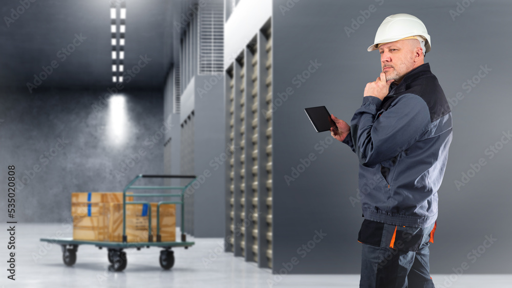 Poster warehouse worker. man with tablet thought. cart with boxes in middle corridor. man is looking for fr