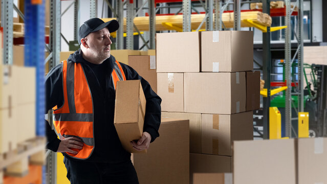 Man inside warehouse. Businessman with boxes. Guy in orange reflective vest. Businessman in warehouse with products. Owner of company is engaged in warehouse work. Businessman among storage racks