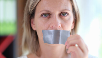 Beautiful woman with duct tape on mouth closeup