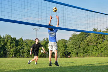 Volleyball player setting his partner in a doubles grass game