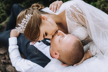 Obraz na płótnie Canvas Stylish young groom and beautiful bride with a tiara are kissing. Close-up wedding photography, portrait.