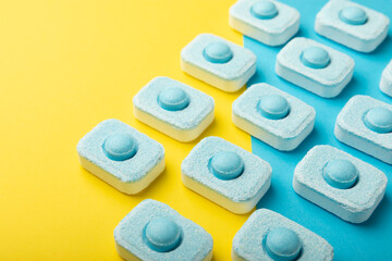 Tablets for softening water on a yellow background. Capsules for washing machines and dishwashers, preventing limescale. Place to copy.
